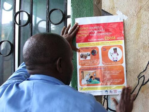 A nurse sets an information sign about Ebola on a wall of a public health center on July 31, 2014 in Monrovia. Liberia announced on July 30 it was shutting all schools and placing 