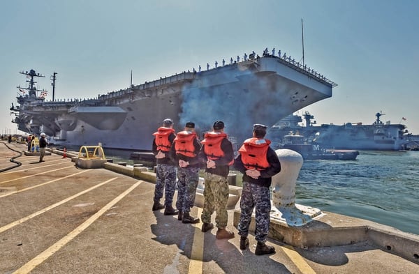 Norfolk, Va. (April 11, 2018) Their job done, line handlers stand at attention as the carrier Harry S. Truman departs Norfolk Naval Station on deployment. (photo by Harold J. Gerwien)