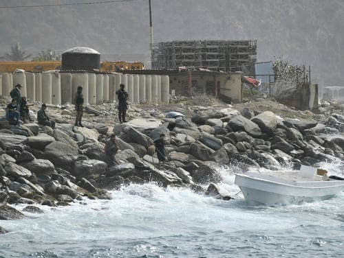 Security forces guard the shore area and a boat in which authorities claim the group of armed men landed in the port city of La Guaira, Venezuela, Sunday, May 3, 2020. (AP Photo/Matias Delacroix)