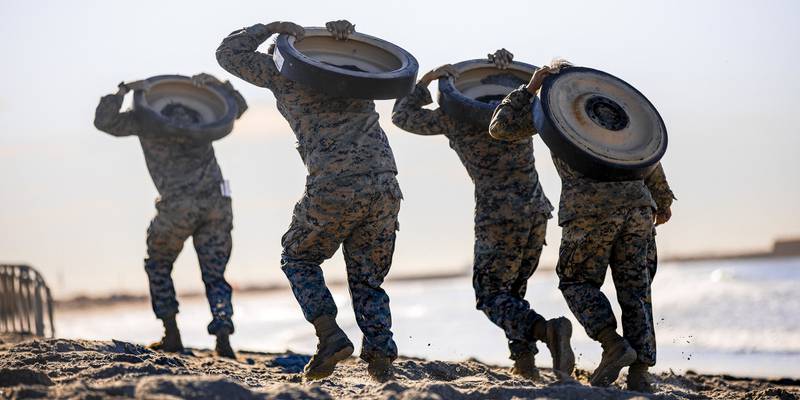 Marines with 1st Marine Division carry track wheels during the Amphibious Combat Endurance Test on Marine Corps Base Camp Pendleton, Calif., Jan. 15, 2021.