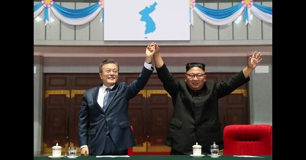 South Korean President Moon Jae-in and North Korean leader Kim Jong Un raise their hands after watching the mass games performance of 
