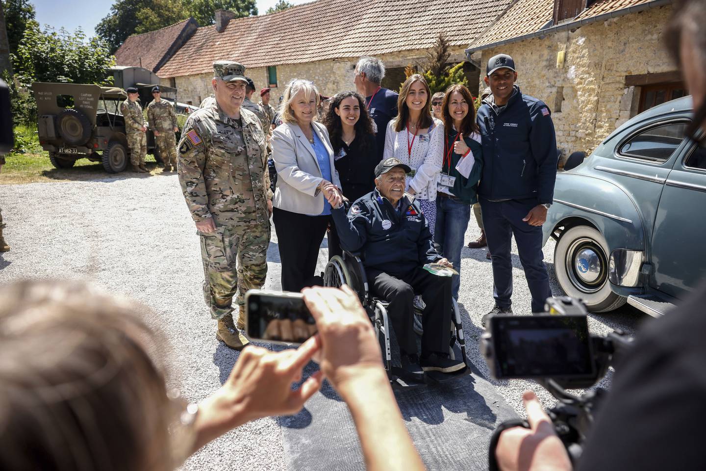 U.S. Gen. Mark Milley, left, his wife Hollyanne Milley, 2nd left, veteran Sgt. Andrew Negra, center on wheel chair, and his family pose for a group photo during a gathering in preparation of the 79th D-Day anniversary in La Fiere, Normandy, France, Sunday, June 4, 2023.