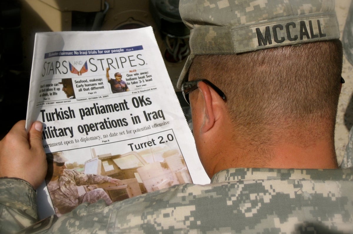 uniformed service member reading Stars and Stripes newspaper