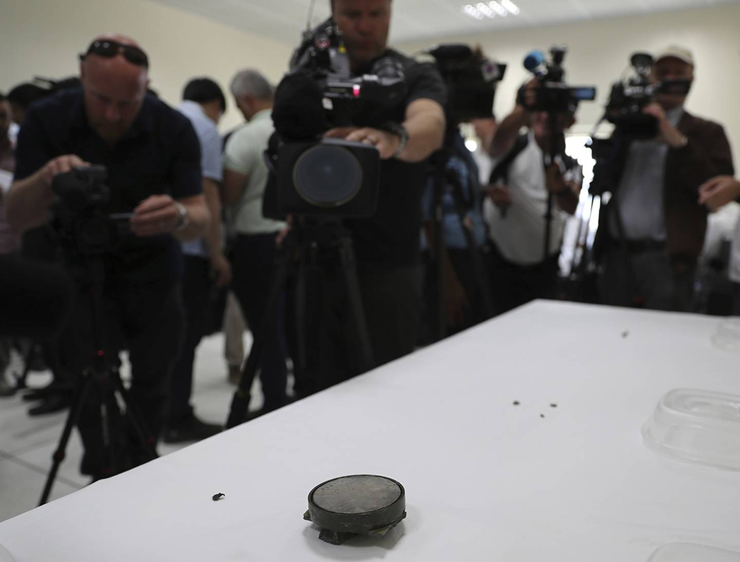 Journalists take pictures of a magnet the U.S. Navy says came from a limpet mine that didn't explode on a Japanese-owned oil tanker at a 5th Fleet base