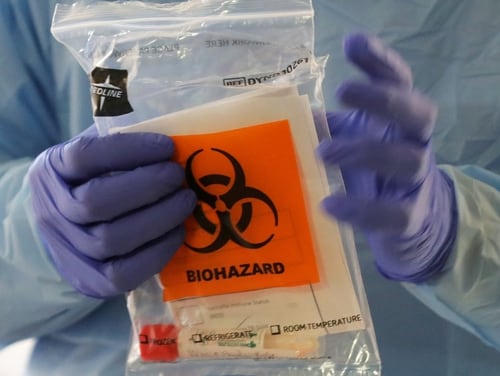 A nurse at a drive up COVID-19 coronavirus testing station, set up by the University of Washington Medical Center, holds a bag containing a swab used to take a sample from the nose of a person in his or her car. (Ted S. Warren/AP)