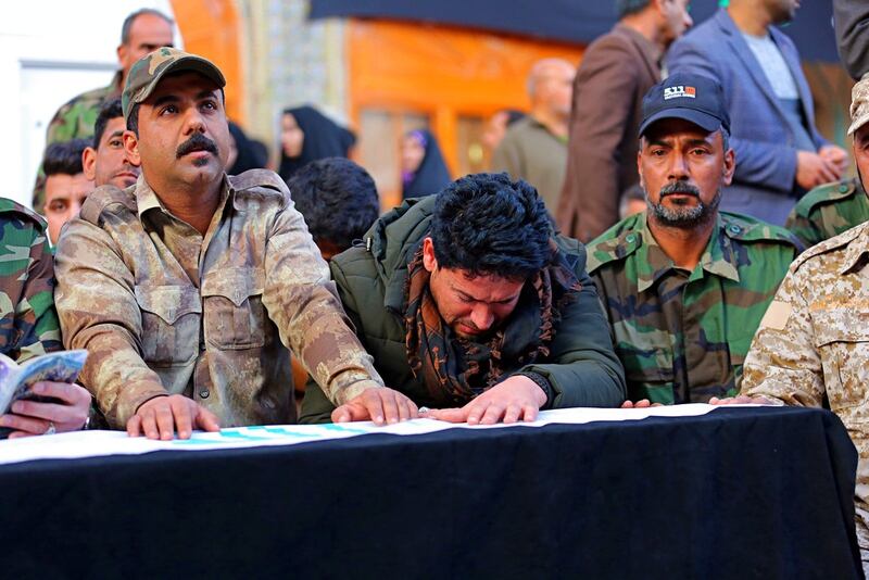 Mourners pray over the flag-draped coffin of Ismail Mahmoud, 24, a fighter of the Popular Mobilization Forces, who was killed Sunday in an attack southwest of the northern city of Kirkuk, during his funeral in Najaf, Iraq, Monday, Feb. 19, 2018. (Anmar Khalil/AP)