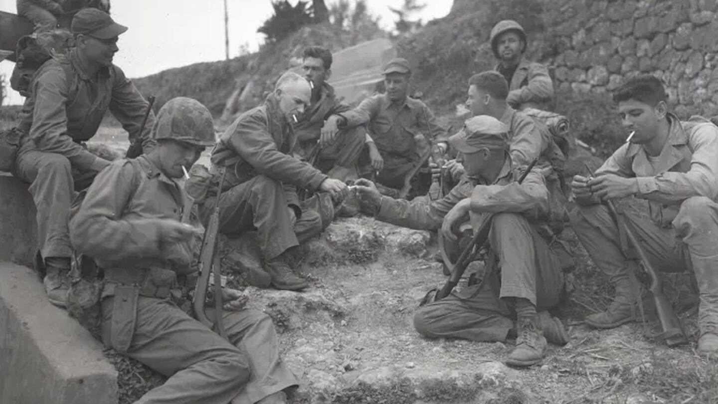 Columnist Ernie Pyle rests on the roadside with a Marine patrol on April 8, 1945. (Photo by Barnett, courtesy of the U.S. National Archives)