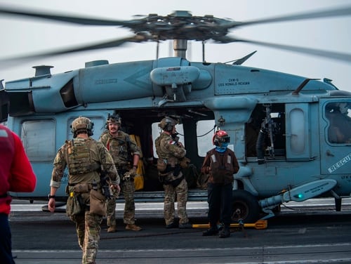 Sailors assigned to an EOD unit board an MH-60S Seahawk helicopter on the flight deck of aircraft carrier USS Ronald Reagan to head to an oil tanker that was attacked off the coast of Oman in the Arabian Sea on Friday, July 30, 2021. (Quinton A. Lee/U.S. Navy, via AP)