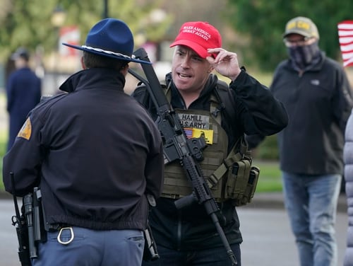 An armed supporter of President Donald Trump speaks casually with a Washington State Patrol trooper during a rally on Jan. 10, 2021, at the Capitol in Olympia, Wash. (Ted S. Warren/AP)