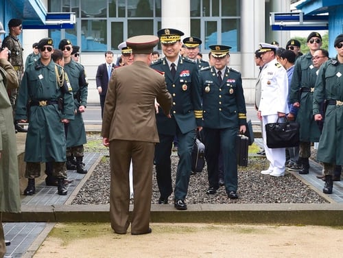 In this photo provided by the South Korea Defense Ministry, South Korean Maj. Gen. Kim Do-gyun, center right, shakes hands with a North Korean officer as he crosses to North Korea for the meeting at the northern side of Panmunjom in the Demilitarized Zone, North Korea, Thursday, June 14, 2018. The rival Koreas were holding rare high-level military talks Thursday to discuss reducing tensions across their heavily fortified border. (South Korea Defense Ministry via AP).