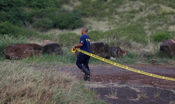 A Honolulu firefighter stretches caution tape across the entrance of Kaena Point, Wednesday, Aug. 16, 2017, in Waialua, Hawaii. An Army helicopter with five on board crashed several miles off Oahu's North Shore late Tuesday. Rescue crews are searching the waters early Wednesday. (Marco Garcia/AP)