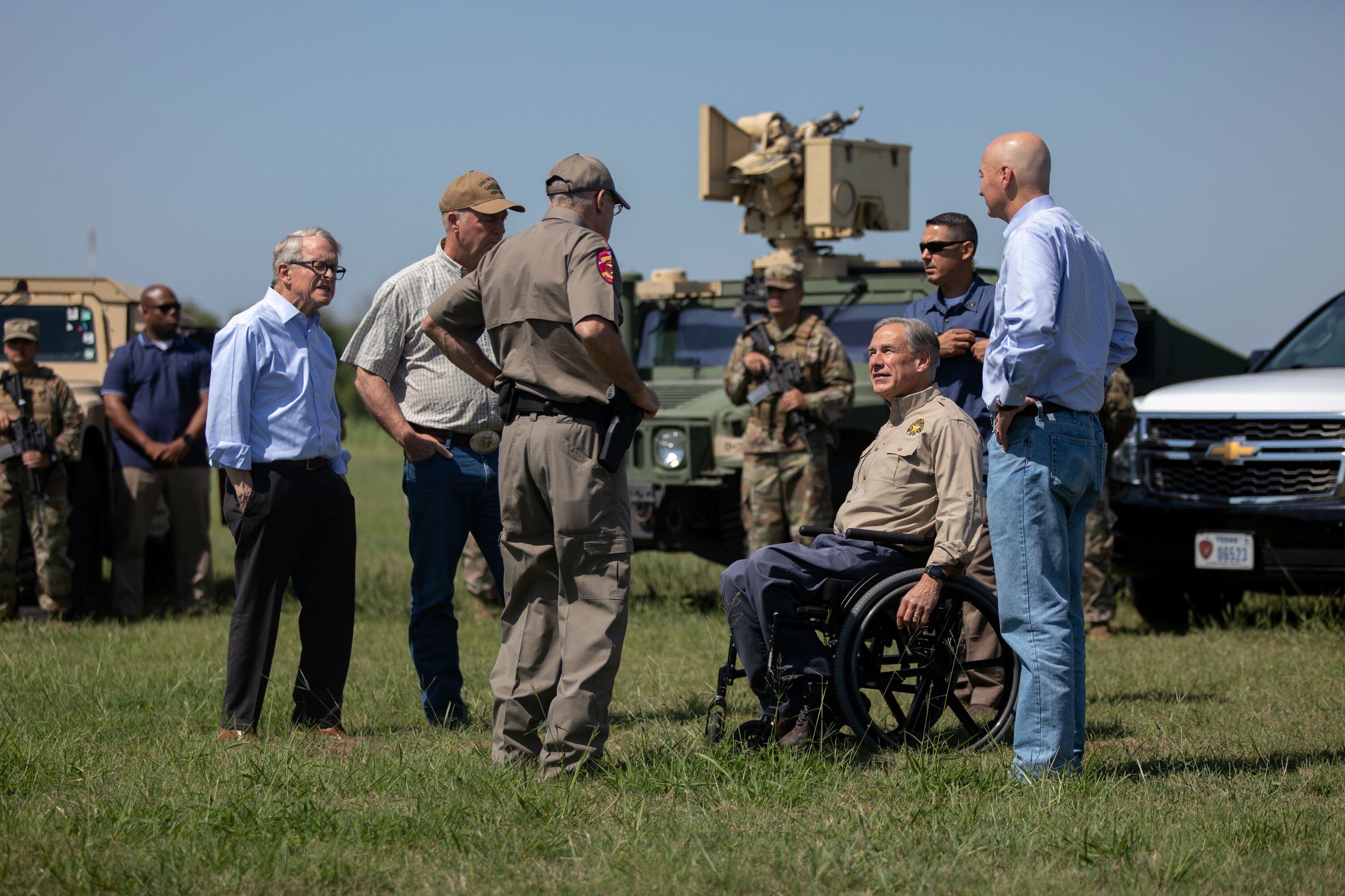 Flanked by National Guard members, Gov. Greg Abbott speaks with Texas Department of Public Safety Director Steve McCraw prior to a press conference with nine other governors at Anzalduas Park in Mission on Oct. 6, 2021. (Eddie Gaspar/The Texas Tribune)