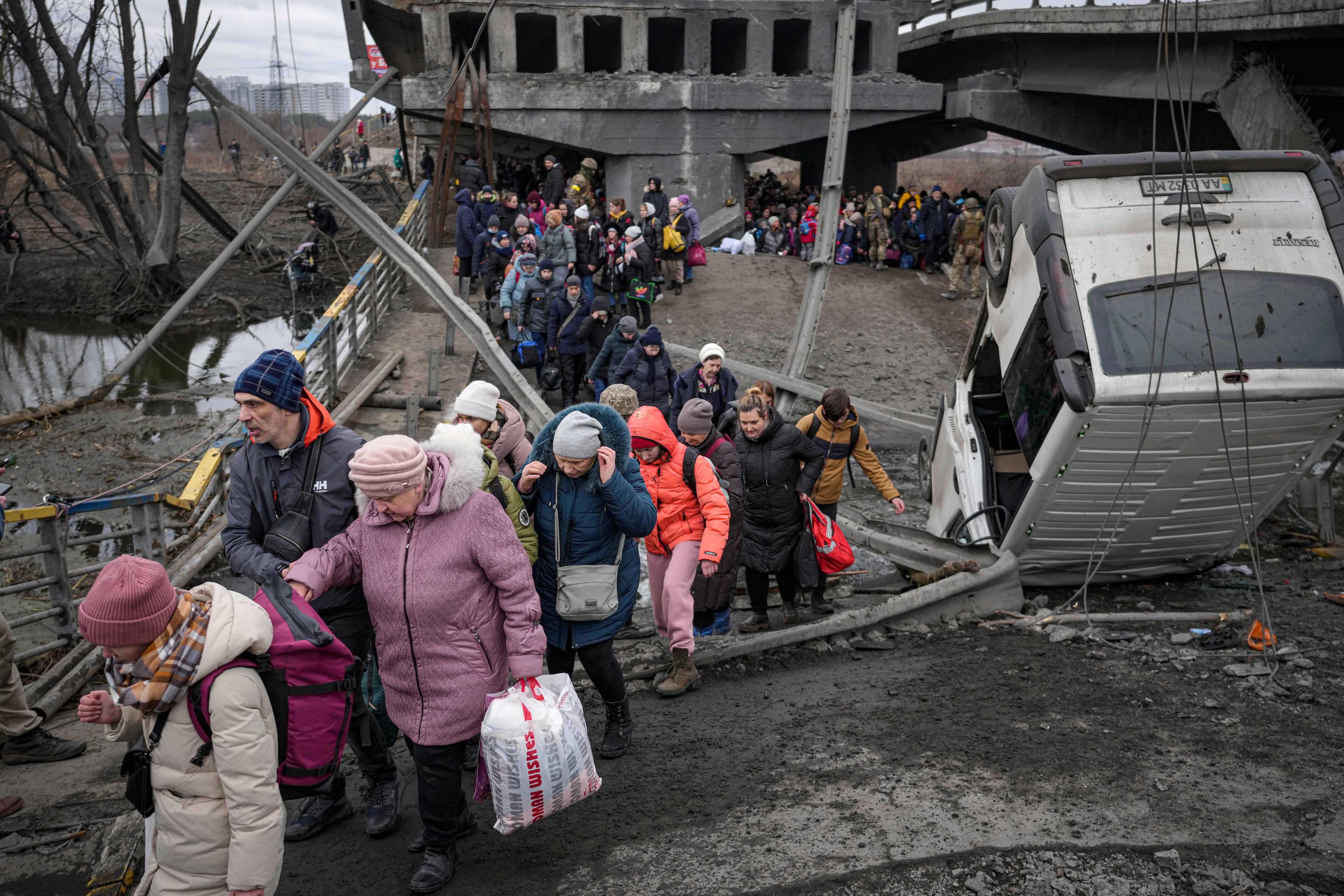 People cross on an improvised path under a bridge that was destroyed by a Russian airstrike, while fleeing the town of Irpin, Ukraine, Saturday, March 5, 2022. (Vadim Ghirda/AP)