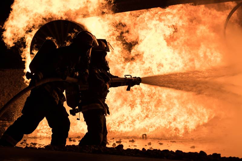 Brent Hardsaw, 22nd Civil Engineer Squadron fire inspector, and Airman 1st Class Trace James, 22nd CES fire protection apprentice, extinguish flames during an annual night aircraft burn, Sept. 18, 2020, at McConnell Air Force Base, Kan.