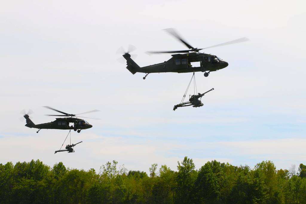 Two UH-60 Black Hawk helicopters of the 101st Combat Aviation Brigade, 101st Airborne Division, sling-load howitzers during an air assault demonstration at Fort Campbell, Kentucky.