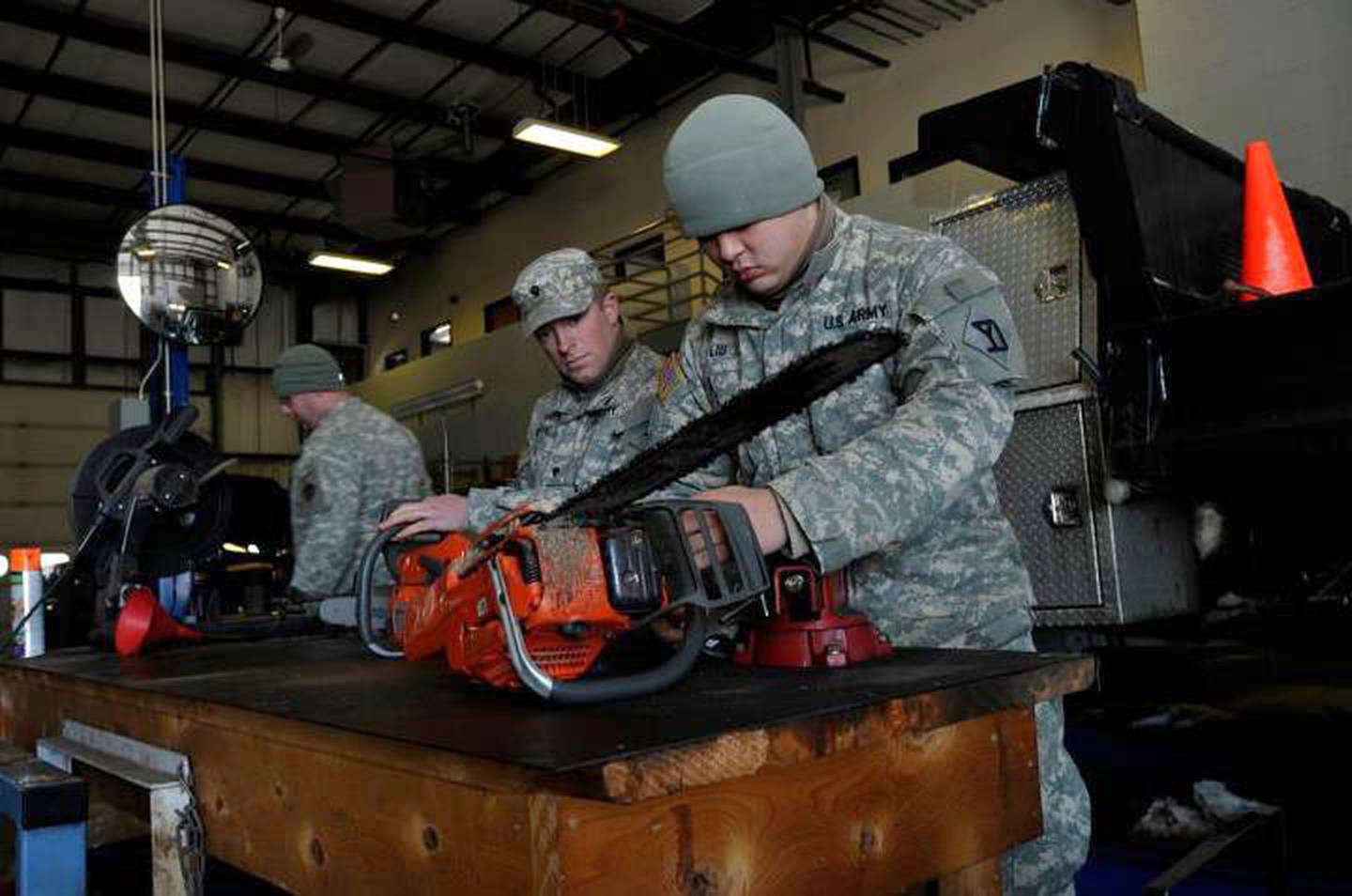 Army Spcs. Chris DeLano, center, and David Liu, right, perform maintenance on chainsaws used to cut fallen trees and clear roads after winter storm Nemo in Plymouth, Massachusetts, Feb. 10, 2013.
