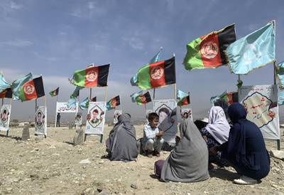 In this Sept 14, 2020, file photo, families and friends of students who were killed in local conflicts gather at the graves of their relatives, adorned with their pictures, on the outskirts of Kabul, Afghanistan.