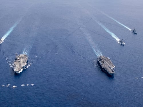 Aircraft from Carrier Air Wings (CVW) 5 and 17 fly in formation over the Nimitz Carrier Strike Force on July 6, 2020, in the South China Sea. The aircraft carriers USS Nimitz (CVN 68), right, and USS Ronald Reagan (CVN 76) and their carrier strike groups are conducting dual carrier operations in the Indo-Pacific as the Nimitz Carrier Strike Force. (MC3Keenan Daniels/Navy)