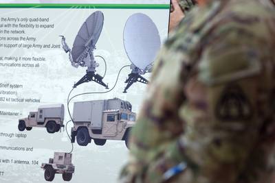 A man stands in front of a poster showcasing networking equipment at a Delaware National Guard event on Aug. 9, 2022.