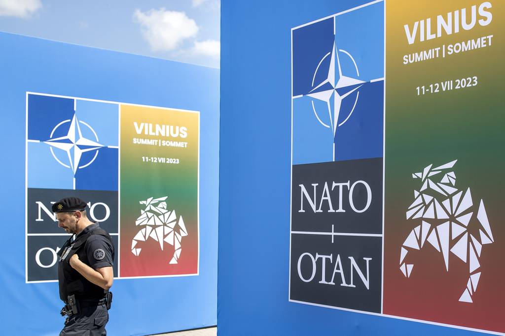 A security guard walks in front of a banner outside the venue of the NATO summit in Vilnius, Lithuania, Sunday, July 9, 2023.