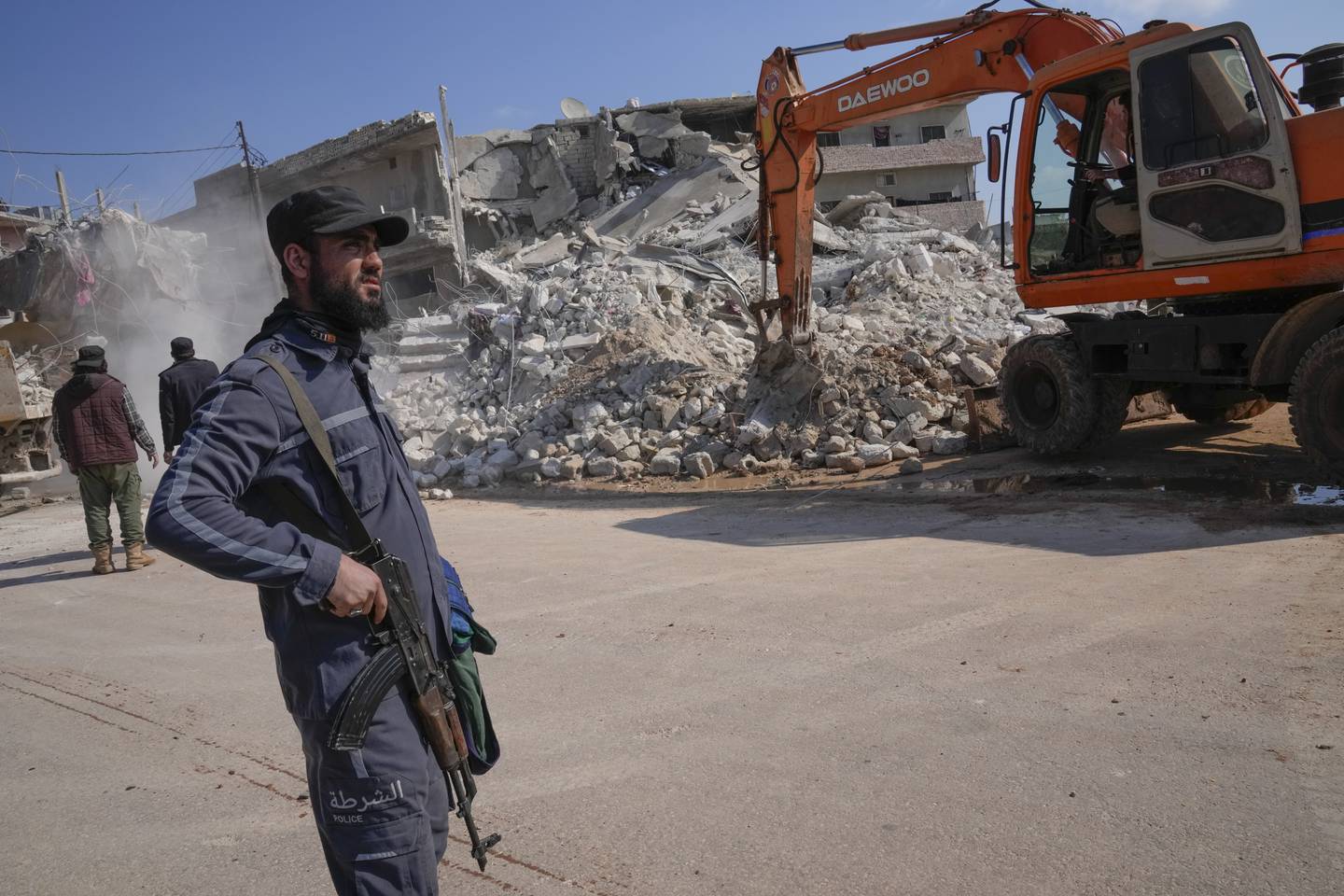 An al-Qaida-linked Hayat Tahrir al Sham militant stands in front of a destroyed house in Atareb, Syria, Sunday, Feb. 12, 2023.