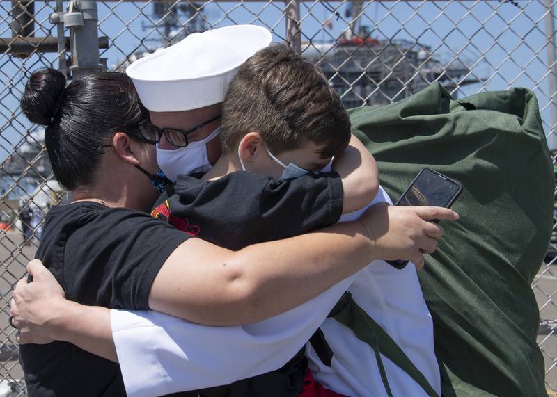 Electronics Technician 1st Class Vincent Testagrossa, assigned to the guided-missile destroyer USS Russell (DDG 59), hugs his family following Russell’s return to Naval Base San Diego on July 8, 2020, after a six-month deployment in support of maritime security operations and theater security cooperation efforts in the U.S. 7th Fleet area of operations.