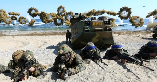 U.S. Marines, left, and South Korean marines, wearing blue headbands on their helmets, take positions after landing on the beach during the joint military combined amphibious exercise Ssangyong on March 12, 2016. (Kim Jun-bum/Yonhap via AP)