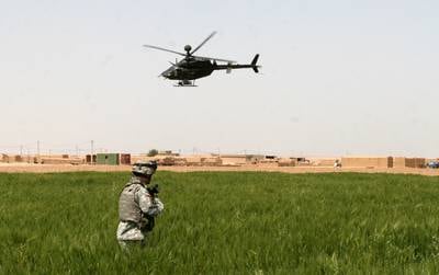 A soldier from Company C, 1st Battalion, 327th Infantry Regiment, pulls security in a town near Kirkuk, Iraq, as a Kiowa Warrior helicopter from 2nd Squadron, 17th Cavalry Regiment, patrols the area surrounding the village in 2006.