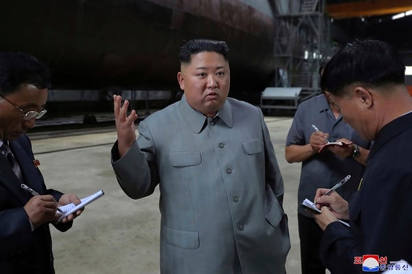 In this undated photo provided on Tuesday, July 23, 2019, North Korean leader Kim Jong Un, center, speaks while inspecting a newly built submarine to be deployed soon, at an unknown location in North Korea. (Korean Central News Agency/Korea News Service via AP)