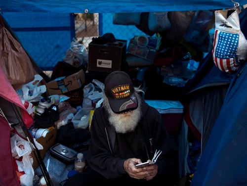 Theodore Neubauer, a 78-year-old Vietnam War veteran who is homeless, looks at his smartphone while sitting in his tent on Dec. 1, 2017, in Los Angeles. (Jae C. Hong/AP)