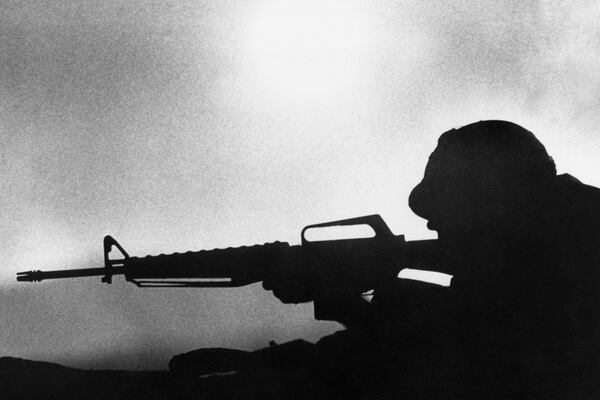 The setting sun silhouettes a U.S. Marine firing his rifle into suspected North Vietnamese positions at the encircled the Sanh Base, March 18, 1968. (AP Photo)
