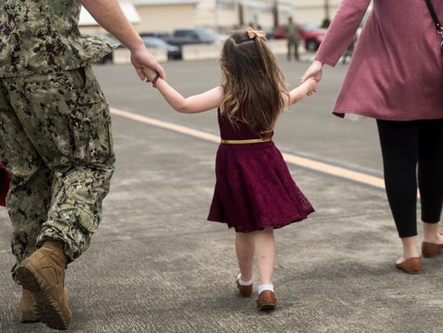 A U.S. sailor and his wife walk together while holding the hands of their daughter during a homecoming, April 2018. A stop-movement order is delaying redeployments for many units. (Sgt. Alex Kouns/Marine Corps)