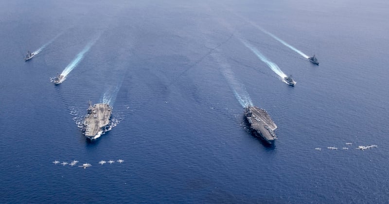 Aircraft from Carrier Air Wings 5 and 17 fly in formation over the Nimitz Carrier Strike Force July 6 in the South China Sea. The aircraft carriers Ronald Reagan, left, and Nimitz, and their carrier strike groups, were conducting dual carrier operations in the Indo-Pacific as the Nimitz Carrier Strike Force. (MC3 Keenan Daniels/Navy)
