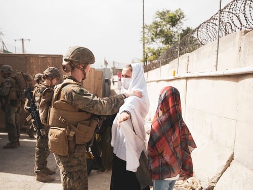 A sailor checks civilians at a checkpoint during the evacuation at Hamid Karzai International Airport, Kabul, Afghanistan, Aug. 18. (Staff Sgt. Victor Mancilla/Marine Corps)