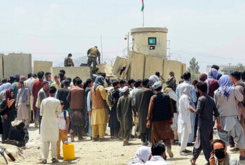 حراس الأمن الأفغان يقفون على الحائط بينما يتجمع مئات الأشخاص خارج المطار الدولي في كابول ، أفغانستان ، 17 أغسطس (AP)