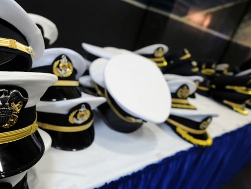 Navy senior enlisted and officer covers dot a table during a reception in the hangar of the carrier Ronald Reagan during a Singapore port call in 2008. That port call was the site of 
