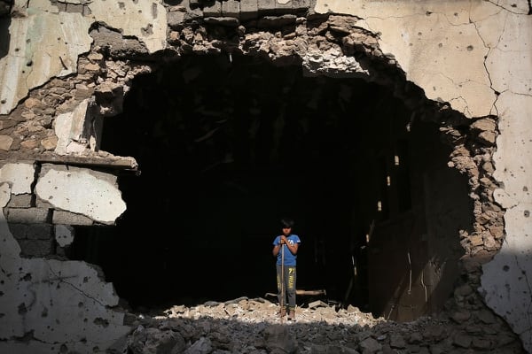An Iraqi boy stands at the entrance of a destroyed building in the old city of Mosul on March 14, 2018, eight months after the Iraqi government forces retook the city from the control of the Islamic State group. (Ahmad al-Rubaye/AFP via Getty Images)