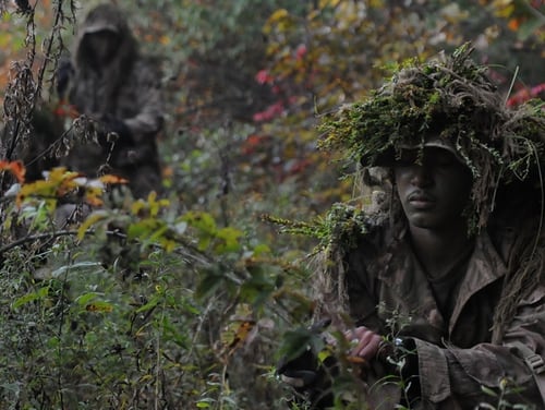 A Marine enrolled in the Scout Sniper Basic Course, clips vegetation to add to his ghillie suit during a stalk exercise on Oct. 15 at Camp Barrett. (Lance Cpl. Emmanuel Ramos/Marine Corps)