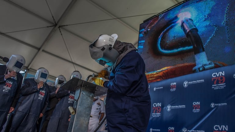 Huntington Ingalls welder Leon Walston places a weld bead over the initials of Caroline Bouvier Kennedy, daughter of the late President John F. Kennedy and the sponsor of the US navy’s next — and second Ford Class aircraft carrier. The ceremony was held at the Newport News, Va. shipyard, adjacent to Dry Dock 12. (Mark D. Faram/staff)