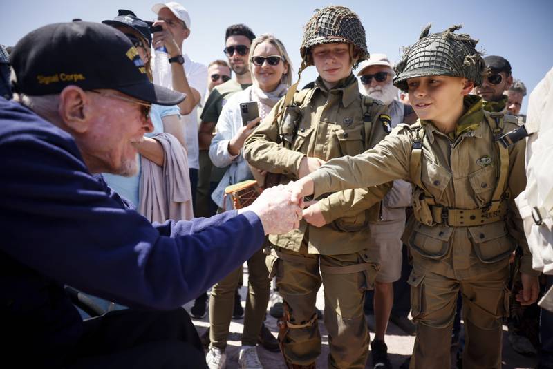 A U.S. veteran shakes hands with a World War II enthusiasts during a gathering in preparation of the 79th D-Day anniversary in Sainte-Mere-Eglise, Normandy, France, Sunday, June 4, 2023.