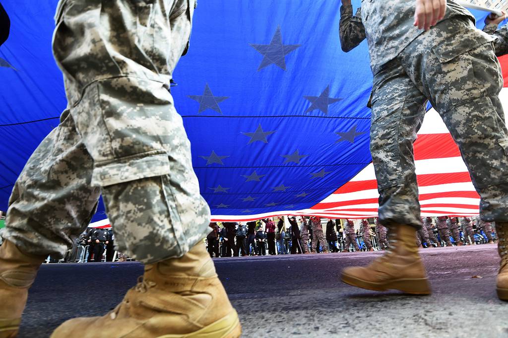 Members of the U.S. military carry a huge American flag as they march during a Veterans Day Parade in New York on Nov. 11, 2014.
