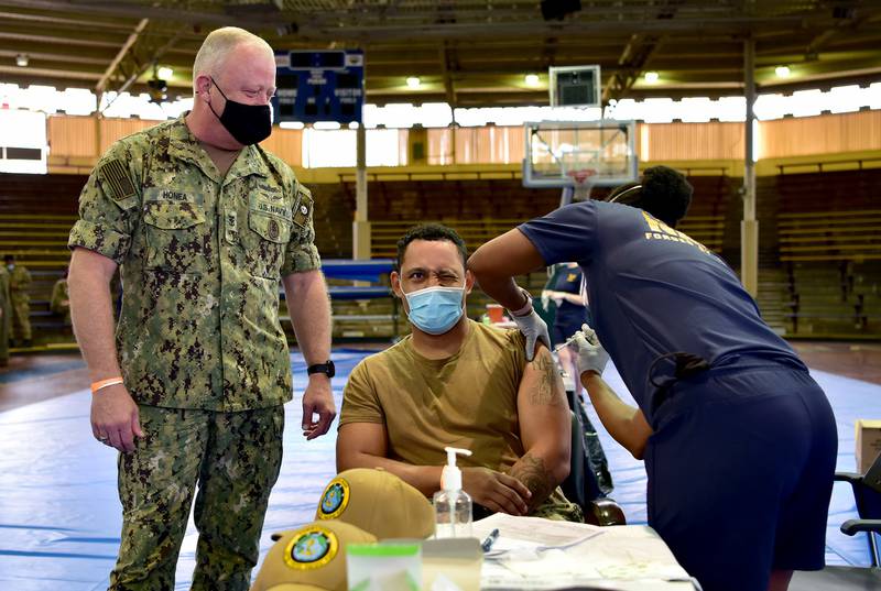 Master-at-Arms 1st Class Patrick Moore receives the COVID-19 vaccine as U.S. Pacific Fleet Fleet Master Chief James Honea observes at Joint Base Pearl Harbor-Hickam, Dec. 29, 2020.