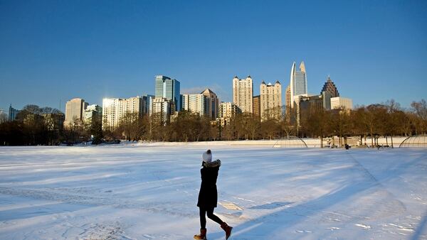 A person walks through a snow covered Piedmont Park as the midtown skyline stands in the background Wednesday, Jan. 17, 2018. Georgia state officials are working to convince the Army to locate the Army Futures Command in the city. (David Goldman/AP)