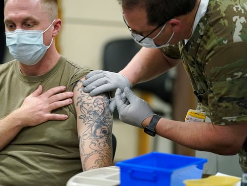Staff Sgt. Travis Snyder, left, receives the first dose of the Pfizer COVID-19 vaccine given at Madigan Army Medical Center at Joint Base Lewis-McChord in Washington. Seventy-percent of active-duty soldiers have received at least one vaccine. (Ted S. Warren/AP)