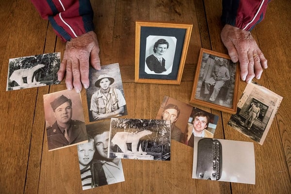 In this photo taken May 8, 2019, Andre Gantois shows family photos, including one of his mother Irene Gantois, top center, in Ludres, France. The retired French postal worker figured he’d likely go to his grave without ever knowing who his father was, unable to identify the U.S. serviceman who had fought his way across France after the D-Day landings, taken a bullet to the skull and been nursed back to health in a military hospital by Gantois’ mother. (Jean-Francois Badias/AP)