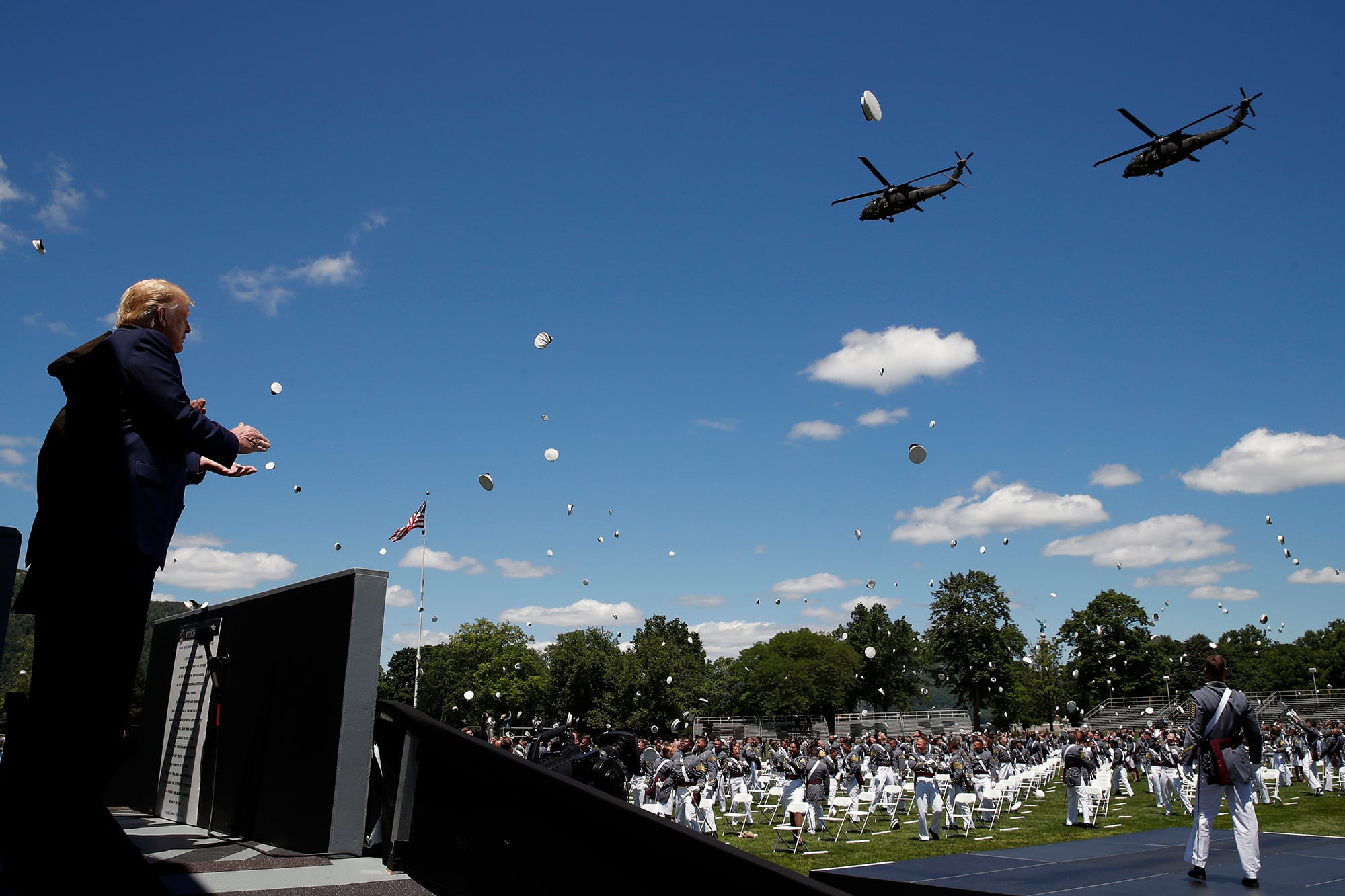 President Donald Trump applauds as Army helicopters fly over and West Point cadets toss their caps into the air at the end of commencement ceremonies on the parade field, at the United States Military Academy in West Point, N.Y., Saturday, June 13, 2020.