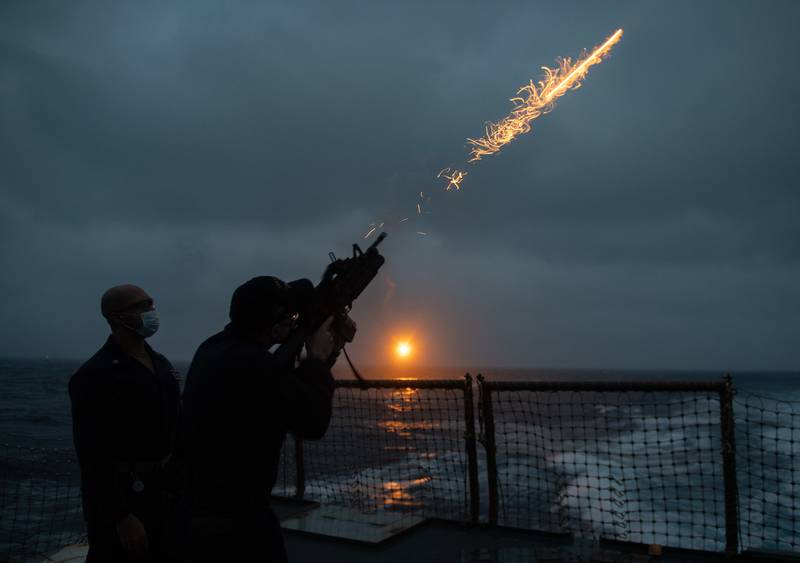 Chief Gunner’s Mate Ricardo Stewart, left, watches as Gunner’s Mate 3rd Class Cullen McArdle fires a flare during a flare exercise in the Philippine Sea aboard the Arleigh Burke-class guided-missile destroyer USS Barry (DDG 52).