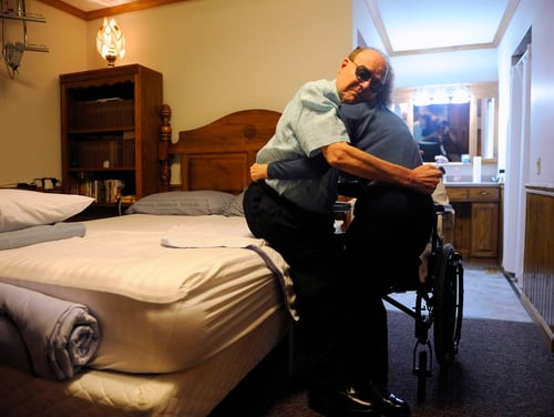 Vietnam veteran Jerry King holds onto his wife, Pauline, as she lifts him into his wheel chair at their home in Anna, Ill., in this Aug. 30, 2013 photo. (Stephen Lance Dennee/AP)