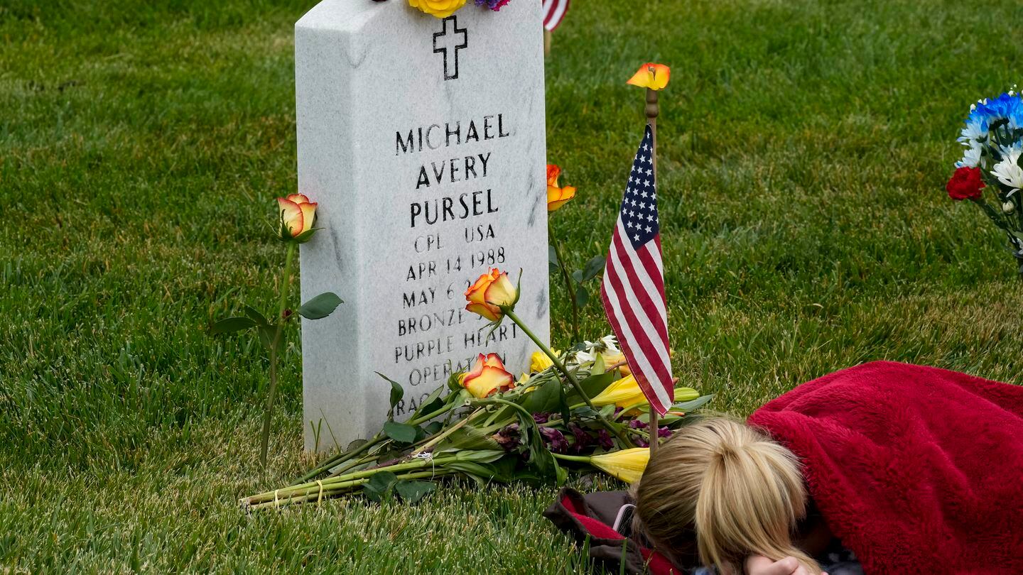 Avery Carlin of Arlington, Va., rests by the headstone of her uncle, Army Cpl. Michael Avery Pursel, as she visits Section 60 at Arlington National Cemetery with her family on Memorial Day, May 29. (Alex Brandon/AP)