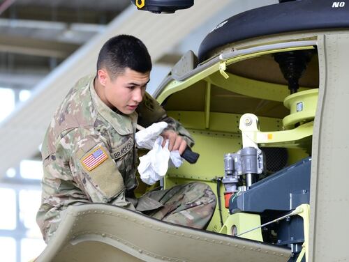A 4th Combat Aviation Brigade soldiers conduct an abbreviated corrosion control inspection on an CH-47 Chinook helicopter. The Army is eliminating some corrosion control training as part of a reduction in administrative tasks. (Charles Rosemond/Army)